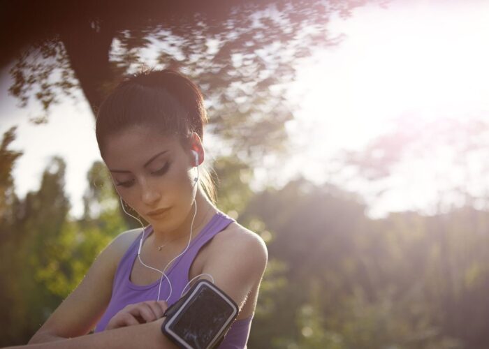 Läuferin mit Kopfhörern und Smartphone beim Training im Freien