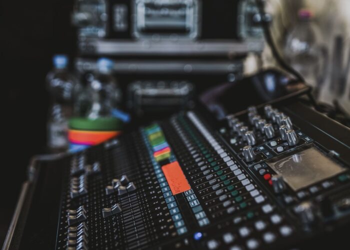 Nahaufnahme eines Audiomischpults mit Reglern und farbigen Pegelanzeigen