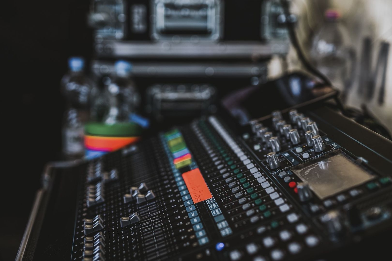 Nahaufnahme eines Audiomischpults mit Reglern und farbigen Pegelanzeigen