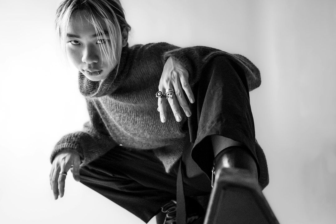 Schwarzweißporträt einer Person in weitem Strickpullover und dunkler Hose