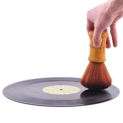 Hand reinigt eine schwarze Vinylschallplatte mit einer weichen Bürste